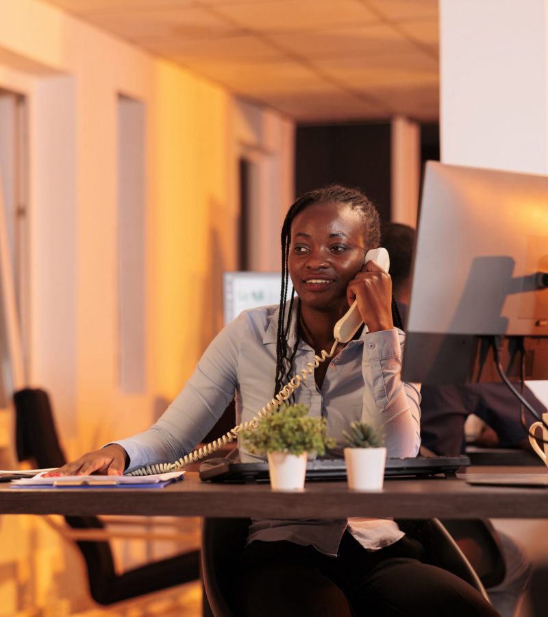 Office secretary answering landline phone call to talk about business research with project manager. Having remote conversation on office telephone line, chatting about email report.